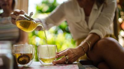 Hands pouring chai tea into a glass mug